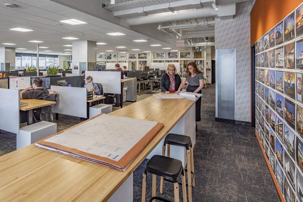 People talking at a long wood table in an open office